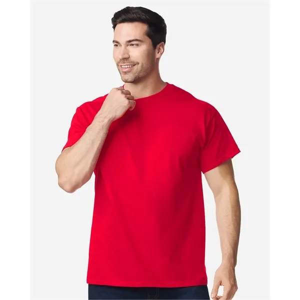 Smiling man wearing a red Gildan Heavy Cotton crew neck t-shirt, the kind of blank used for bulk custom logo apparel